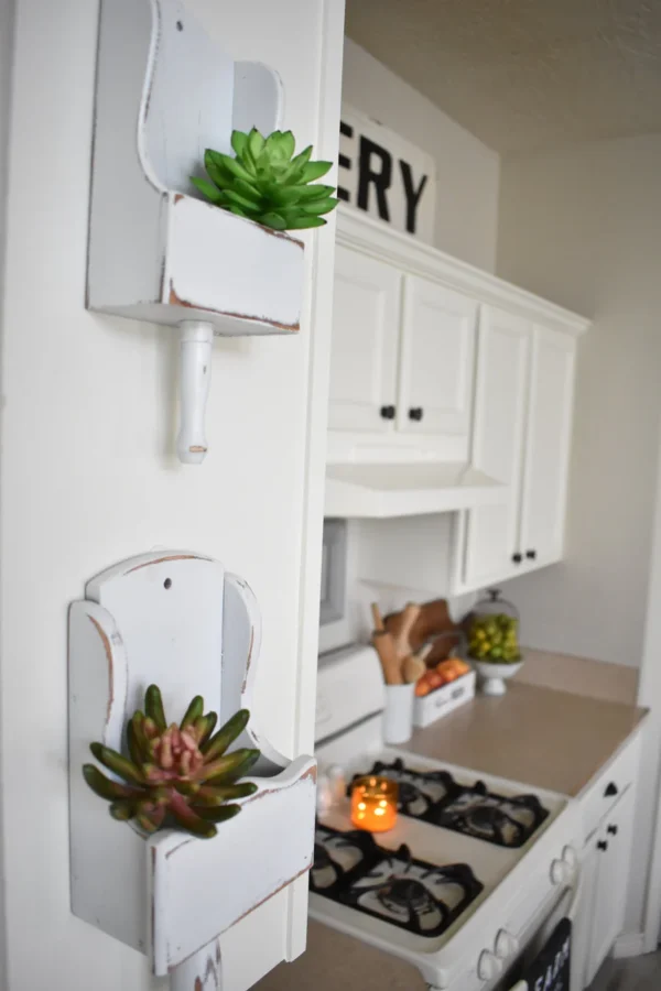 Soportes de pared restaurados con pintura spray mate Rust-Oleum Ultra Cover 2X, mostrando acabado blanco opaco estilo farmhouse en cocina decorada con suculentas