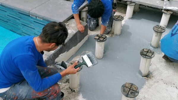 Aplicación de Soudagum Hydro con brocha en superficie junto a piscina como membrana impermeabilizante elástica para evitar filtraciones